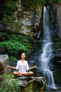 Beautiful young woman meditating in lotus position while doing y
