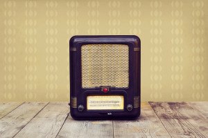 Retro radio on a wooden floor over vintage wallpaper. Toned image