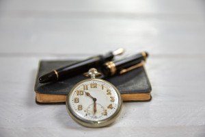 Antique fountain pen old calendar and watch on a white wooden table