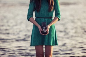 Vintage photo brunette girl with retro camera by the sea