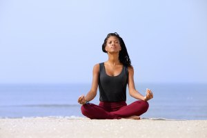 Woman Sitting In Yoga Pose At The Beach