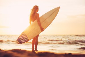 Beautiful sexy surfer girl on the beach at sunset