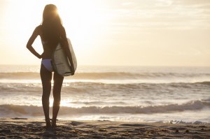Rear view of beautiful sexy young woman surfer girl in bikini wi