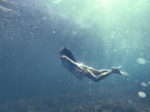 Underwater photo of a human diving in blue sea water