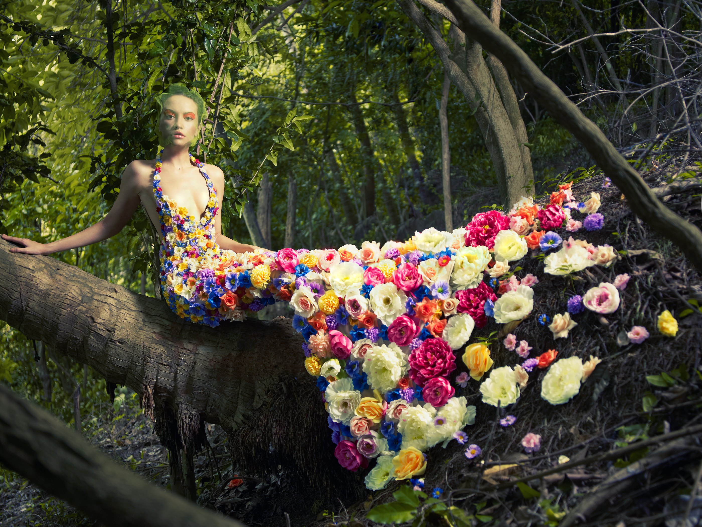 Blooming gorgeous lady in a dress of flowers in the rainforest