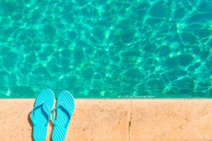 turquoise flip flops at the edge of the pool