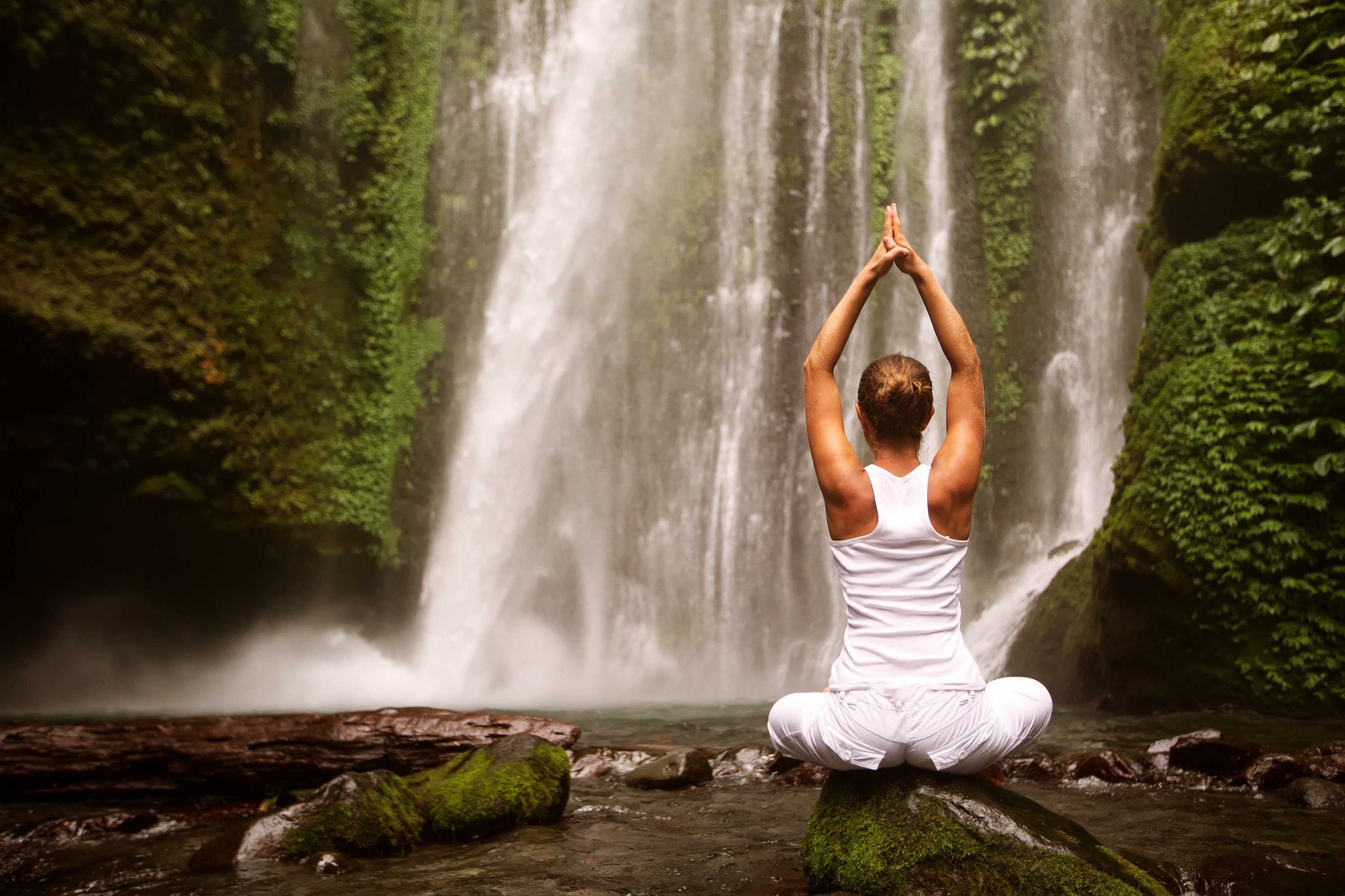 Young Woman Doing Yoga In A Forest Near Waterfall